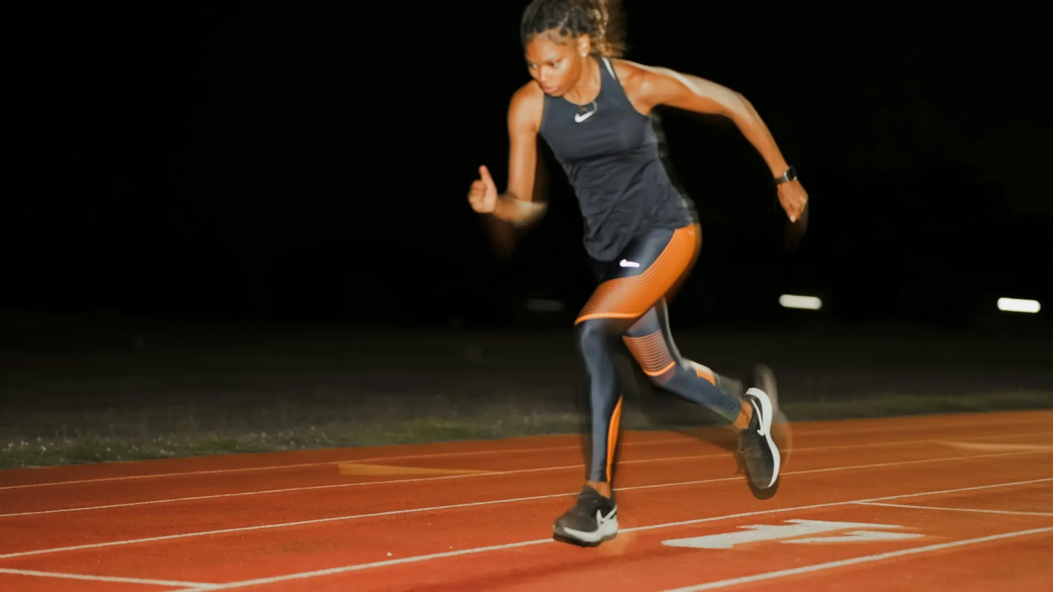 Atleta corriendo en una pista de atletismo de noche