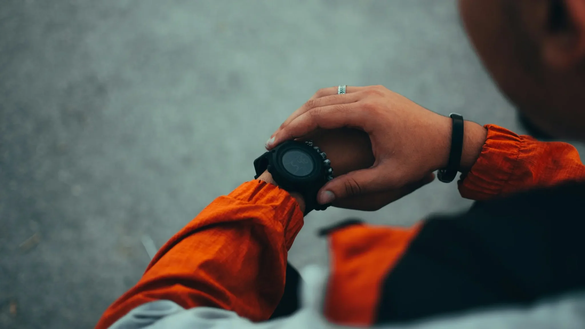 Corredor con chaqueta naranja consultando su reloj deportivo